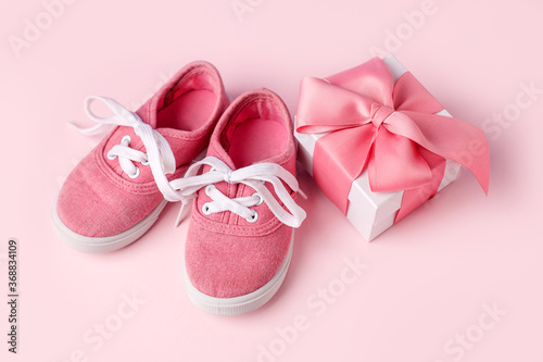 Pink baby shoes and gift present box, concept of first steps, birthday, baby shower, expectation, pregnancy, maternity, motherhood, parenthood. Monochrome card for baby shower party, copy space © misskaterina