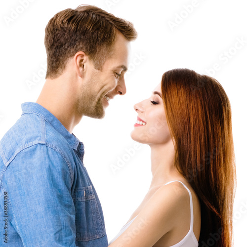 Profile side of smiling happy couple. Portrait image of standing close and looking at each other models in love studio concept, isolated over white background. Man and woman posing. Square composition