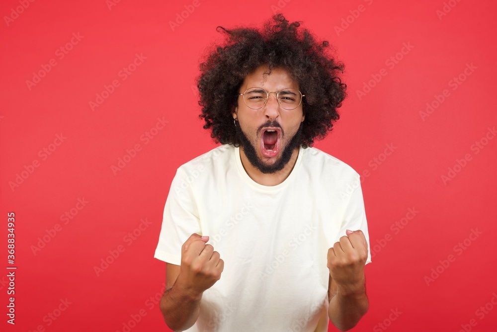 Waist up portrait of strong successful determined young male winner in casual clothes raising arms, clenching fists, exclaiming GOAL with joy and excitement. Victory, success and achievement concept. Waist up portrait of strong successful determined young male winner in casual clothes raising arms, clenching fists, exclaiming GOAL with joy and excitement. Victory, success and achievement concept.