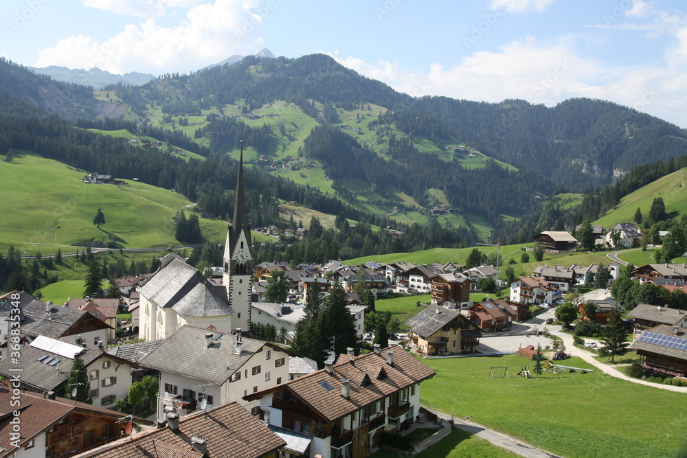 panoramic view of the meadows and mountains of the sella group in alta badia. the typical village with the church