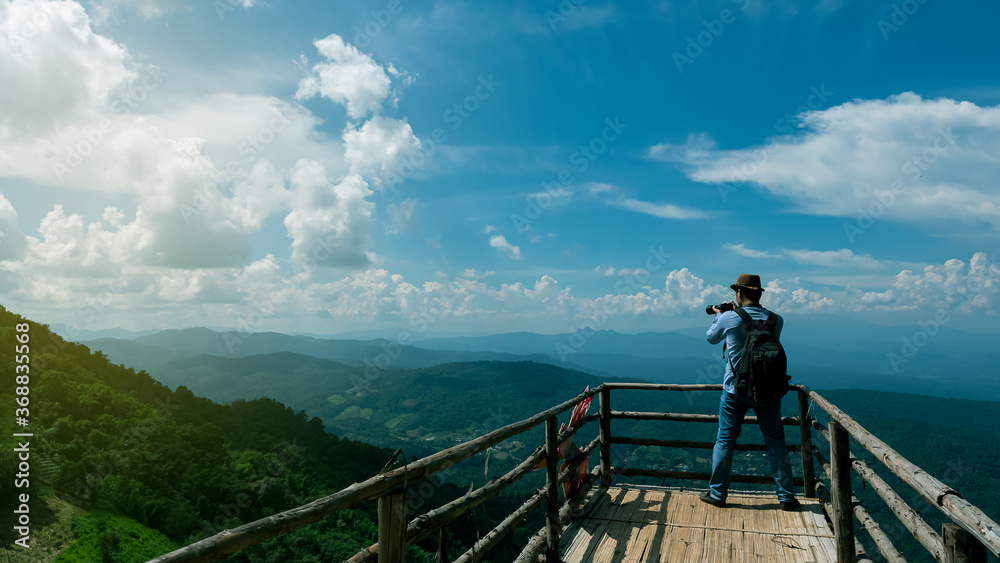 Tourists who stand to take pictures on the bridge to see the view with beautiful mountains and skies with a rear view.