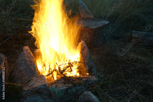 A blazing campfire burns with stones surrounding the fire.