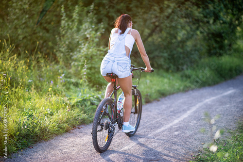 A girl riding a bicycle in a park in summer in the sunny morning.