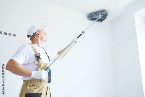 Fototapeta Naklejka Na Ścianę i Meble -  Painter works with triangle drywall cleaning tool. Surface preparation for painting