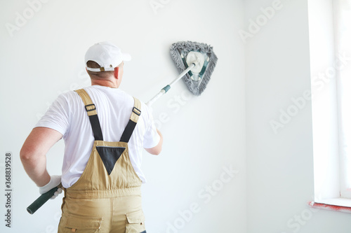 Painter works with triangle drywall cleaning tool. Surface preparation for painting