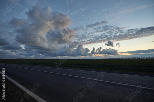 Late evening empty asphalt highway on background of beautiful clouds at sunset