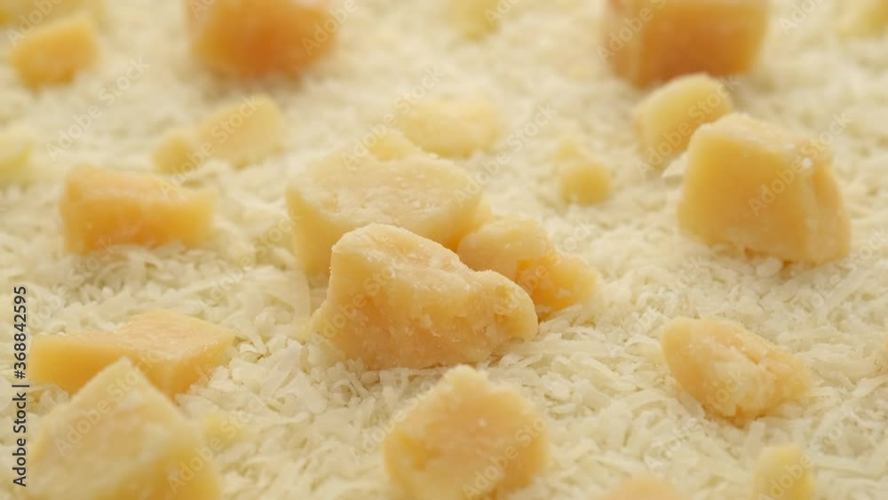 hard cheese parmesan grated and pieces, close up rotating