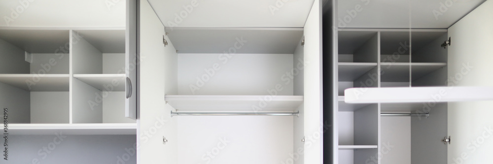 Close-up of empty closet space in room. Many shelves and expanse. Cupboard or wardrobe for people clothes. New purchased property. Moving day and renovation concept Close-up of empty closet space in room. Many shelves and expanse. Cupboard or wardrobe for people clothes. New purchased property. Moving day and renovation concept