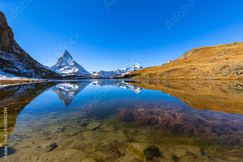 Stunning panorama view of the famous Matterhorn and Weisshorn peak of Swiss Pennine Alps with beautiful reflection in Riffelsee lake on sunny autumn near train station Riffelberg, Valais, Switzerland © Peter Stein