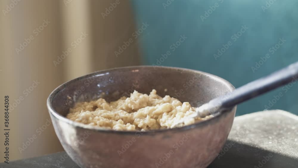 A small ceramic bowl and spoon, healthy steaming breakfast porridge ready to eat A small ceramic bowl and spoon, healthy steaming breakfast porridge ready to eat