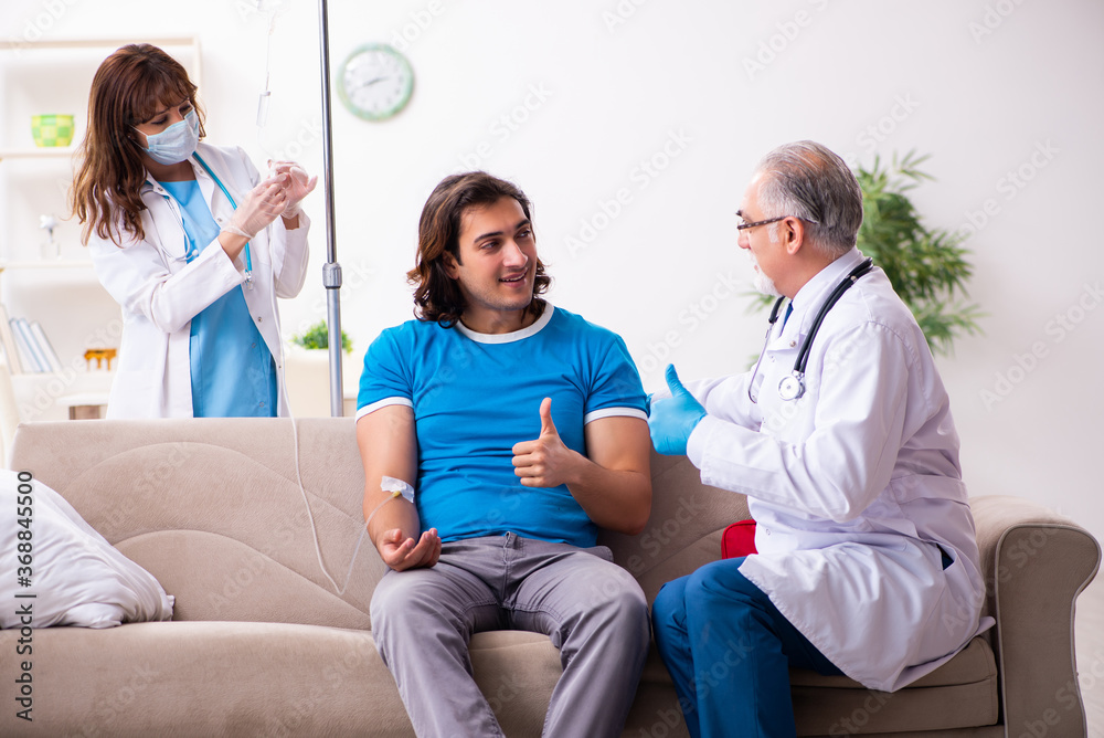 Two doctors visiting sick young man at home Two doctors visiting sick young man at home