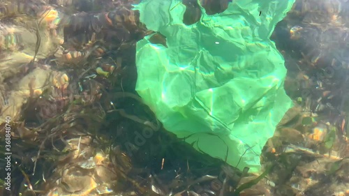 Ocean plastic pollution concept with used old plastic bag floating in the seashore water