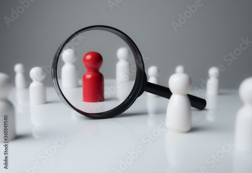 a magnifying glass looking to red wood people,Select a person in the team, Human Resource. photo