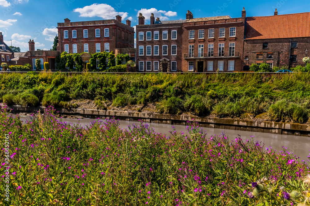 A view across the River Nene towards Georgian buildings on the North Brink in Wisbech, Cambridgeshire in the summertime