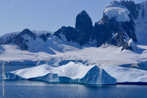 Blue Iceberg in antarctic landscape, with mountains on a sunny day, Antarctica