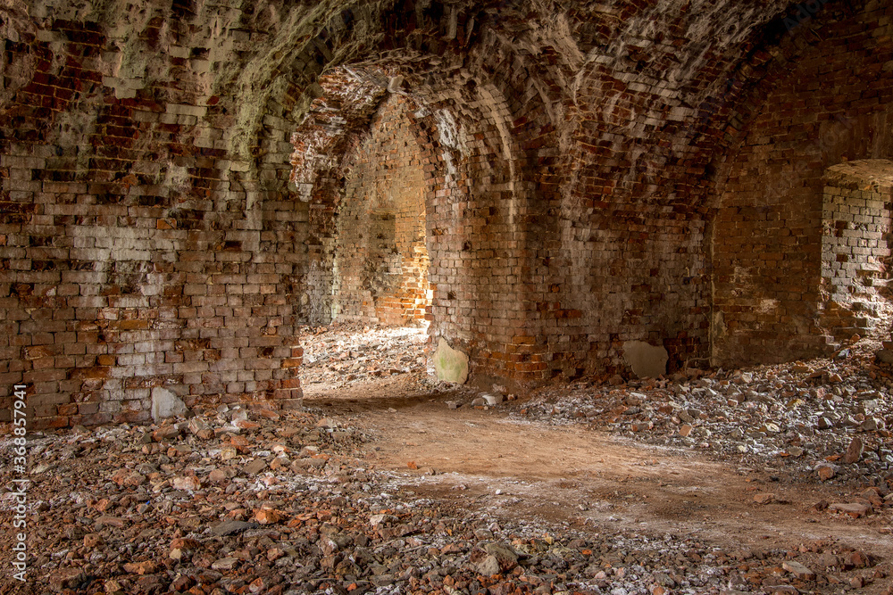 Obraz premium Brick corridor on the lower level in an old abandoned and decaying building