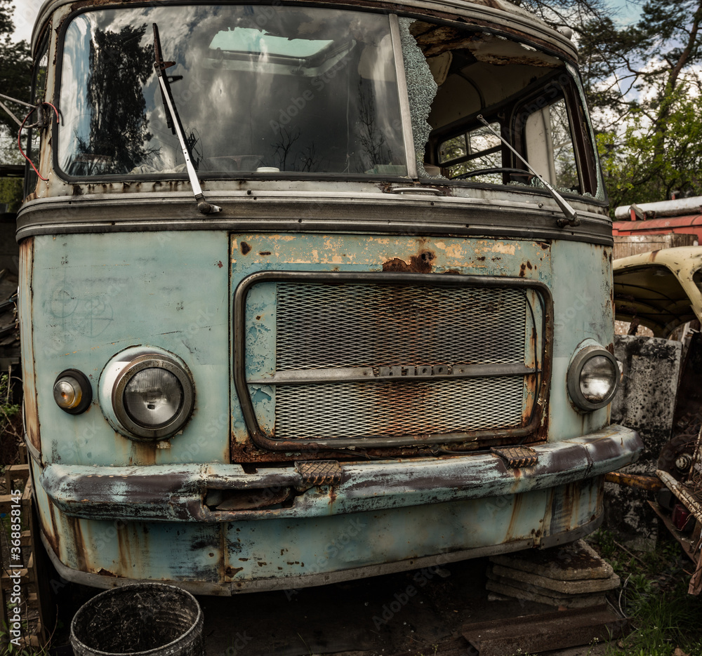 An abandoned bus standing in a forest parking lot among other abandoned vehicles An abandoned bus standing in a forest parking lot among other abandoned vehicles