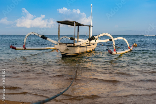 A white siling boat is bound through a blue roap during the touristic visit with cloudy sky background in Bali photo