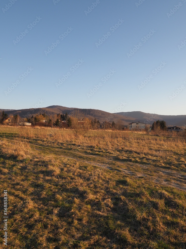 Silesian Beskid Mountains range seen from sport airfield in european Bielsko-Biala city in Poland, clear blue sky in 2020 warm sunny spring day on April at sun set - vertical.