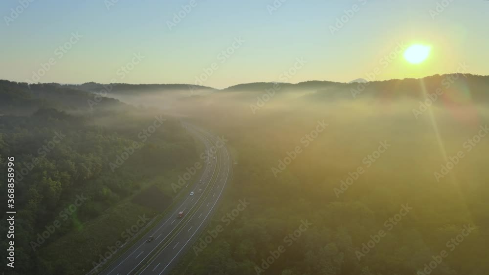 Aerial: highway in countryside covered in morning mist at sunrise Aerial: highway in countryside covered in morning mist at sunrise