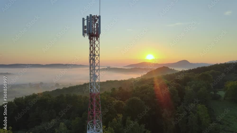 Aerial: European 4G & 5G telecommunication tower on hilltop at sunrise
