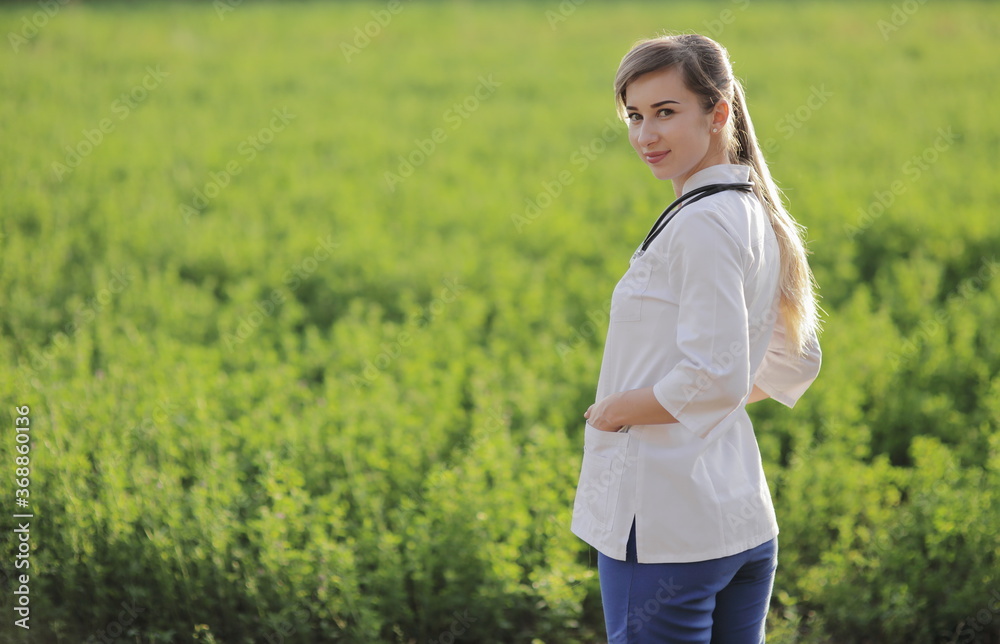 Portrait of a beautiful female doctor or nurse on green grass background