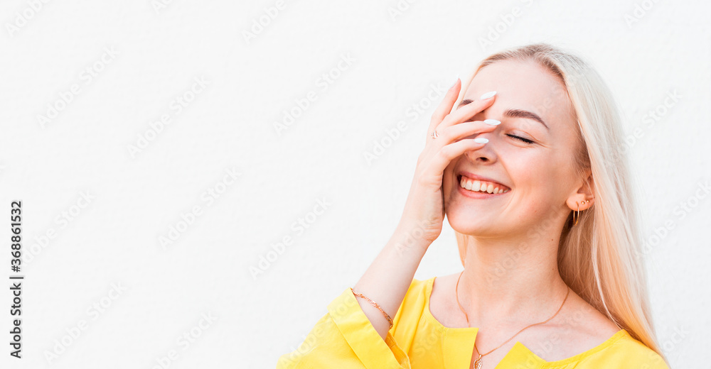 Vivacious woman giglling with her eyes screwed up in a moment of fun as she sitting against white studio wall. Happy natural laughing young casual female covering mouth. Human face expressions Vivacious woman giglling with her eyes screwed up in a moment of fun as she sitting against white studio wall. Happy natural laughing young casual female covering mouth. Human face expressions