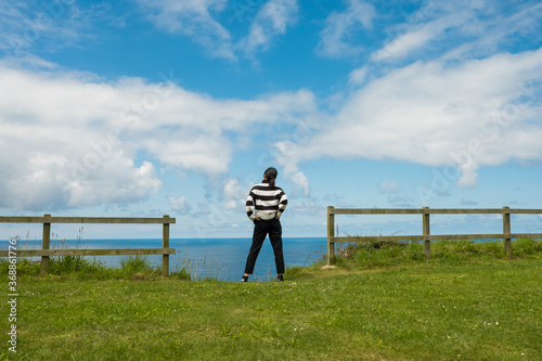 Mujer hispana de mediana edad junto al mar, pensativa mira el horizonte, asturias españa. photo