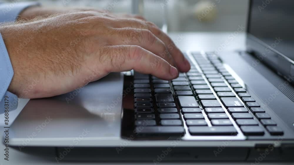 Businessman at the Office Typing on a Laptop Keyboard Sending Messages and Accessing Information from the Internet Businessman at the Office Typing on a Laptop Keyboard Sending Messages and Accessing Information from the Internet