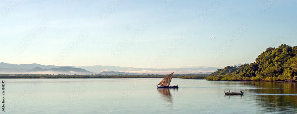 Nosy Be, Madagascar: traditional sailing boat and canoe sail out on the Indian Ocean from Port Ankify, Ambanja district, Northern Madagascar. 