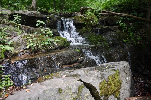 Fototapeta Naklejka Na Ścianę i Meble -  A Small Waterfall Flowing Over Rocks