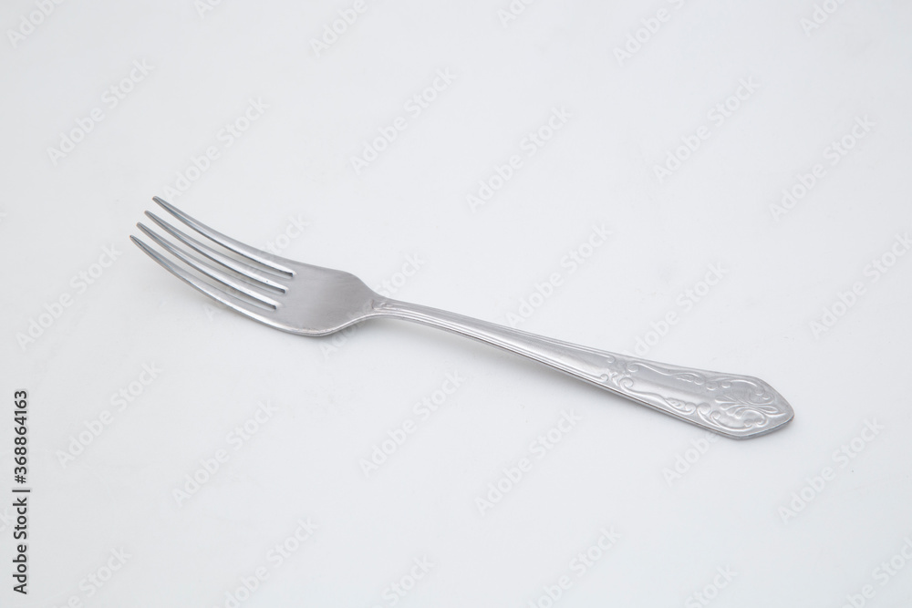 A steel fork lies on a white background. A steel fork lies on a white background.