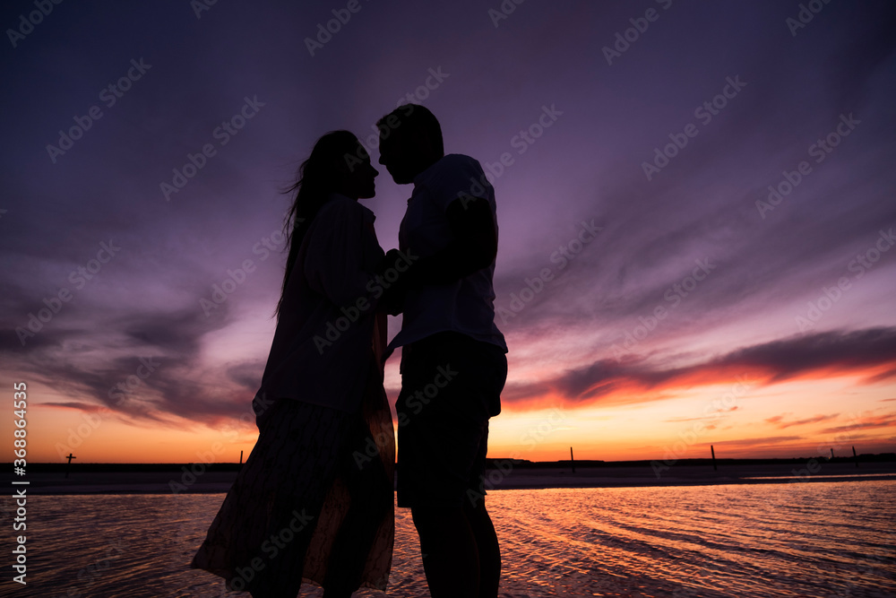 Silhouette of a couple in love at sunset. Photo of lovers at the sea.