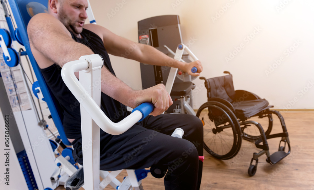 Obraz premium Disabled man doing strength exercises separate from the wheelchair.