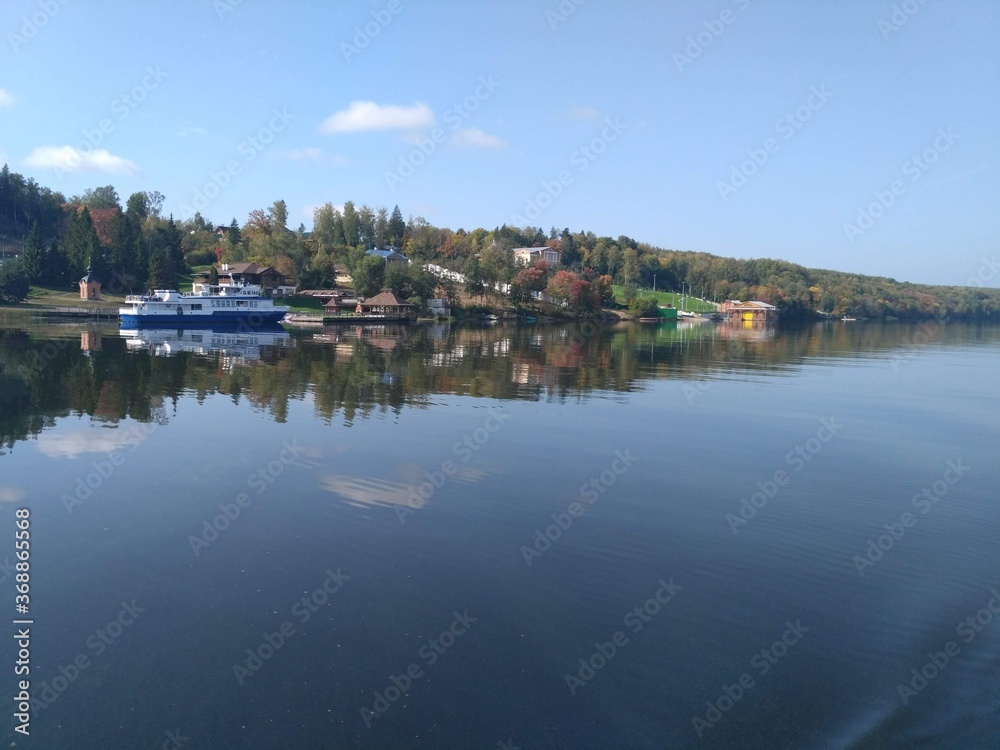 Beautiful Volga coast. Ship at the pier. A magnificent reflection in the mirror of water.