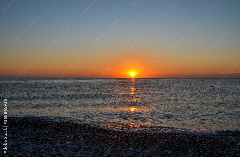 Idyllic scene of sunrise on horizon, red sky and blue sea 
