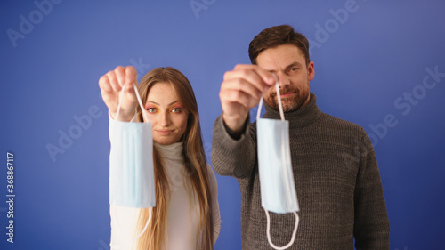 The end of the pandemic. Young couple holding face mask and throws them away. Isolated on blue backgroundHigh quality photo photo