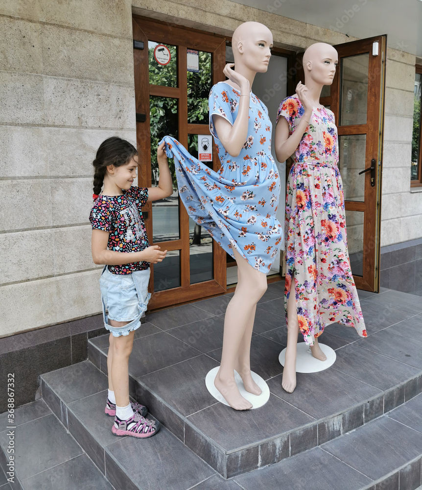 Little girl looks under the dress of a mannequin Stock 写真 Adobe Stock