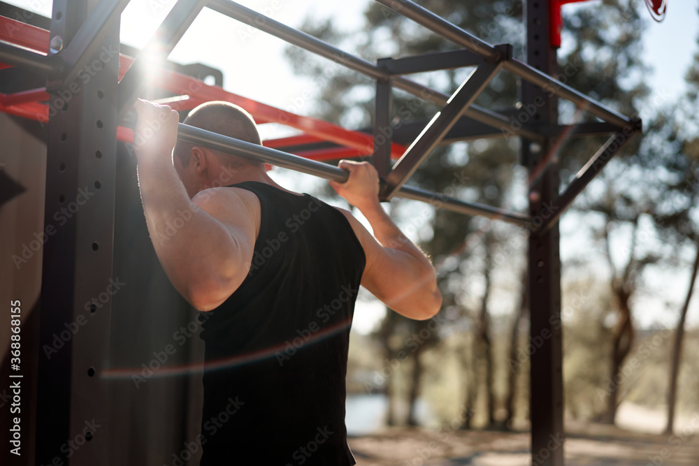 Unrecognizable caucasian men pull-up outdoor workout cross training morning back view