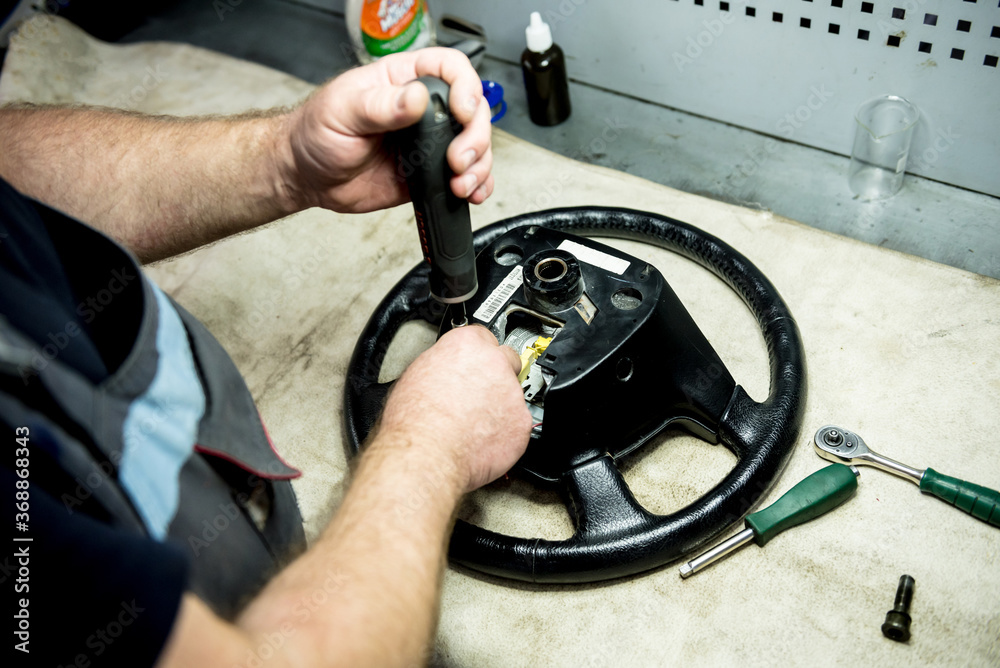 Car mechanic repair steering wheel at service station. Car repair service Car mechanic repair steering wheel at service station. Car repair service