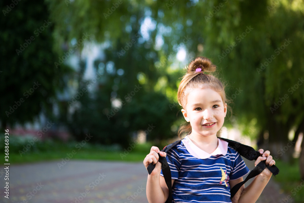 A little girl of Caucasian appearance in a school uniform with a backpack looks into the frame. Concept back to school. Elementary school, developing activities for preschoolers. Space for text A little girl of Caucasian appearance in a school uniform with a backpack looks into the frame. Concept back to school. Elementary school, developing activities for preschoolers. Space for text