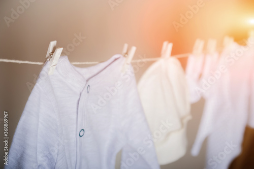 Laundry concept. Cleanliness, ironing, washing of children's clothes. Baby things dry on a rope close-up and copy space on a gray wall background.