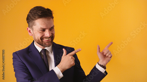 Portrait of cheerful satisfied handsome guy in formal outfit pointing on empty space . High quality photo