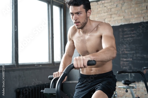 Man using exercise bike at the gym. Fitness male using air bike for cardio workout at Functional training gym.