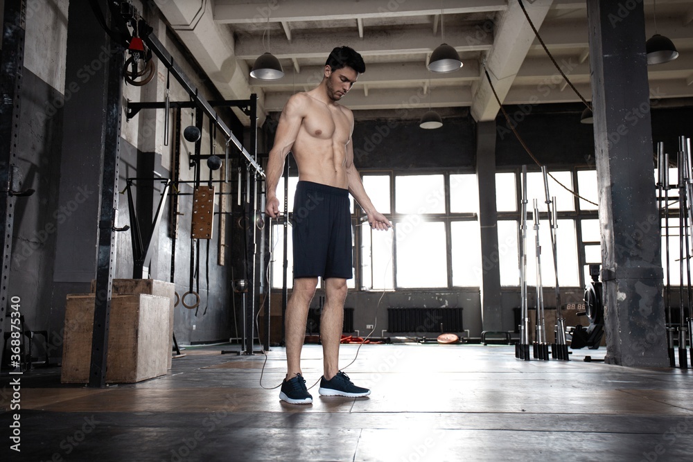 Young sportsman doing jump rope workout in gym