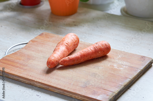 fresh tasty carrot on a wooden cooking board at kitchen table. healthy eating concept.