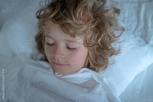 Kids in bedroom sleepin on bed with white sheet and pillow. Eyes closed. photo