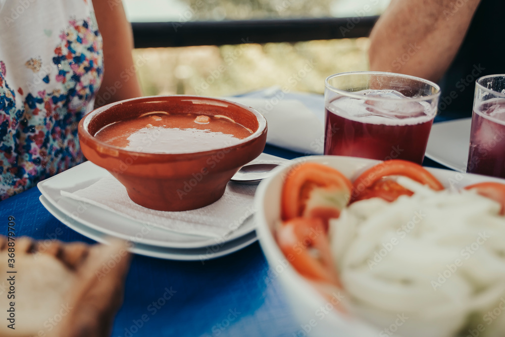 Table of a restaurant with gazpacho and salad.