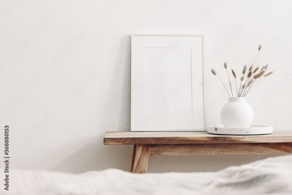 Portrait white frame mockup on vintage wooden bench, table. Modern white ceramic vase with dry Lagurus ovatus grass and marble tray. Blurred beige linen blanket in front. Scandinavian interior. - obrazy, fototapety, plakaty 