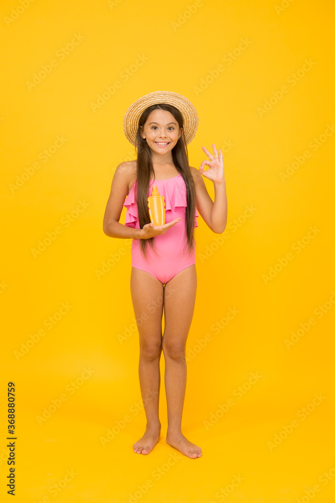 Small girl in swimsuit hold sunscreen cosmetics cream, protecting skin concept Small girl in swimsuit hold sunscreen cosmetics cream, protecting skin concept